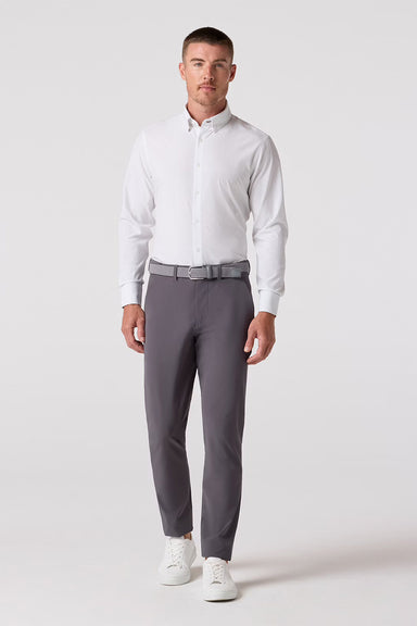 Man wearing a white with green dots dress shirt and gray pants on a white background